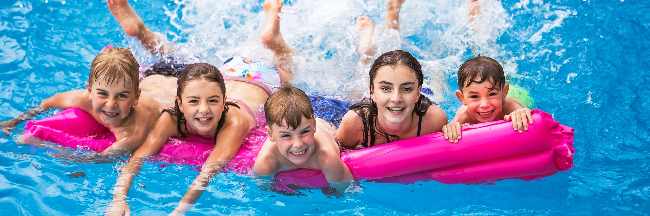 Kinder auf einer Luftmatratze im Schwimmbad